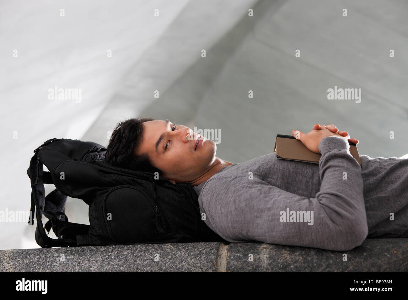 man laying down head resting on back pack Stock Photo