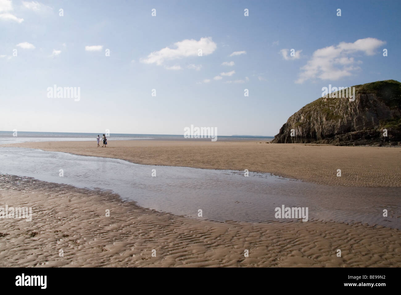 2 people walk alone on the beach at Pendine, Wales, UK Stock Photo