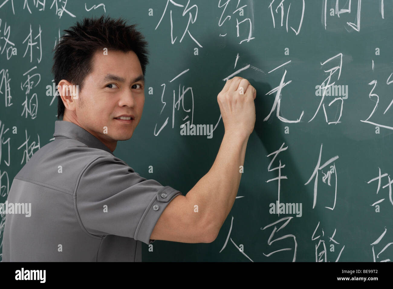 man writing Chinese characters on chalk board Stock Photo