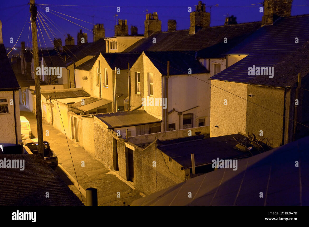 The backs of houses and rear entrances from an alley at night, lit by sodium lights, in Ulverston Cumbria UK Stock Photo