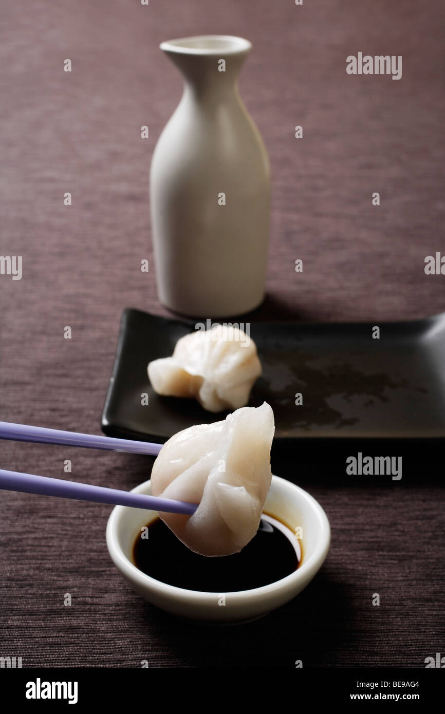 chopstick dipping dim sum in soy sauce Stock Photo