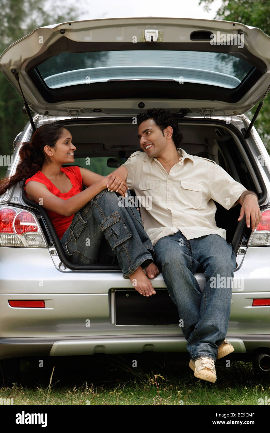 Young couple sitting in car boot Stock Photo