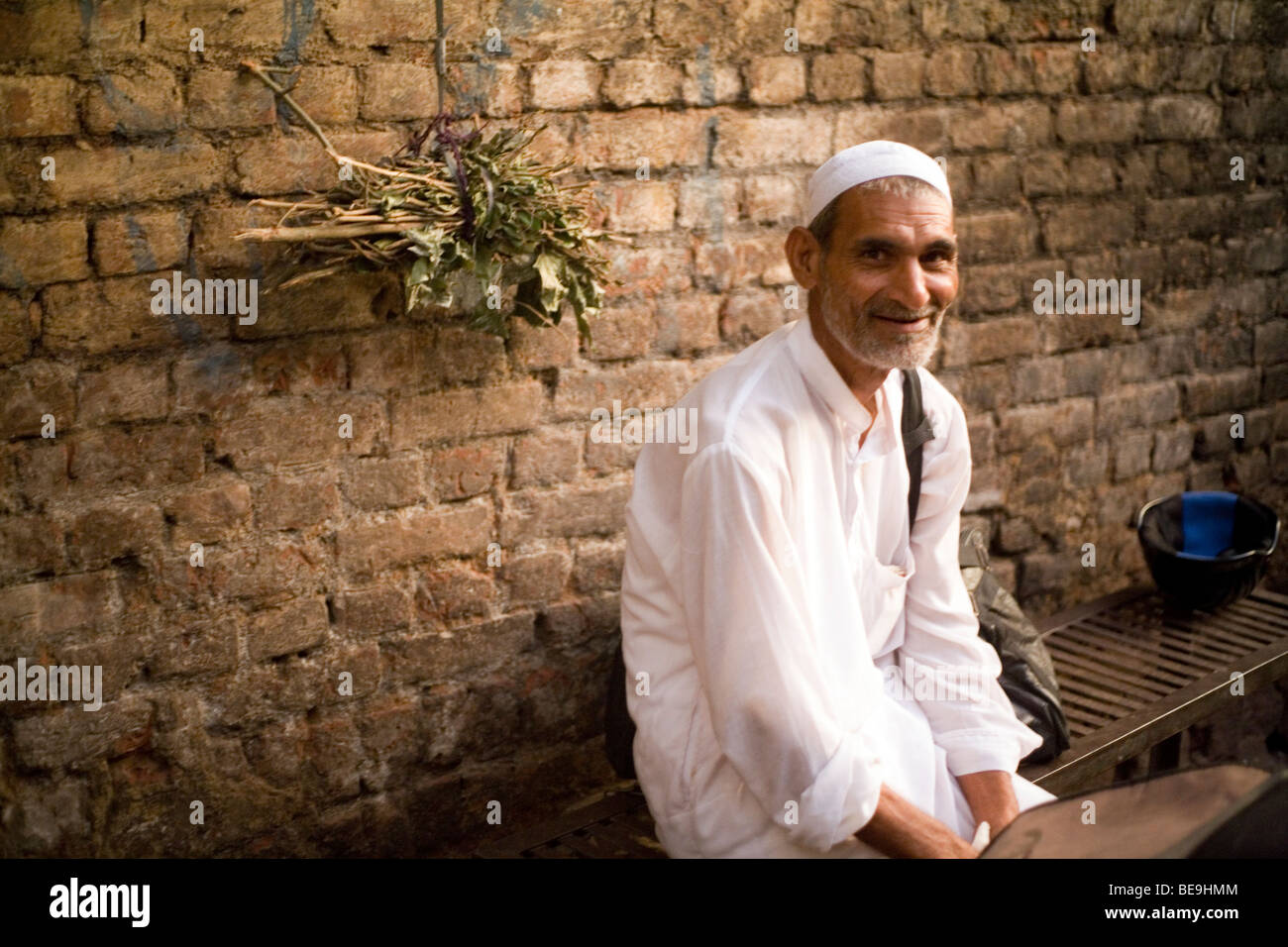 An old man waits for the evening prayer to start in a street in Nizamuddin, New Delhi, India Stock Photo