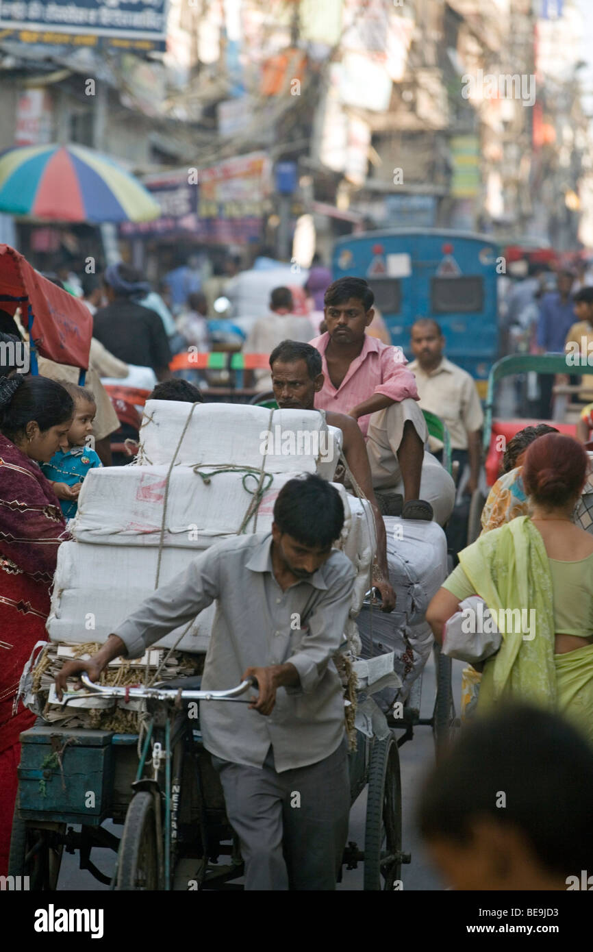 A rickshaw wallah pulls a heavy load through the congested streets of Old Delhi, India Stock Photo