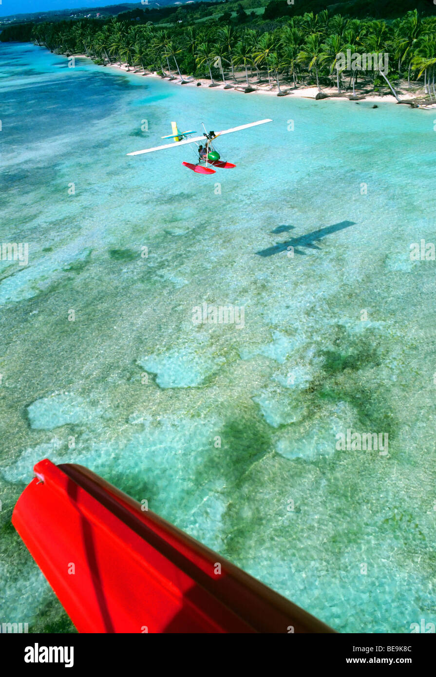 Ultra light seaplane in flight over Caribbean lagoon and beach Stock