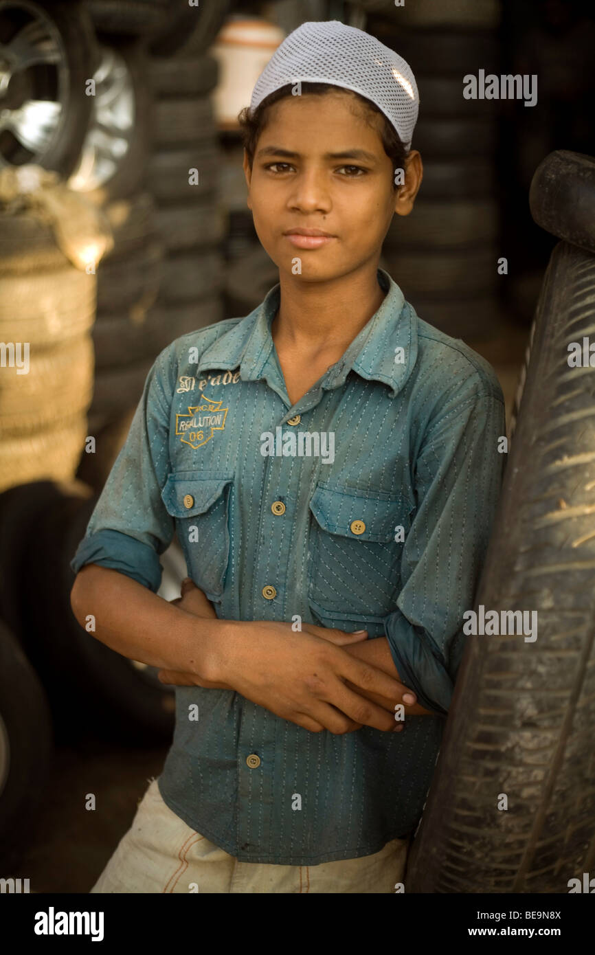 A boy leans against a tyre outside a shop in the Car Parts Bazaar (or