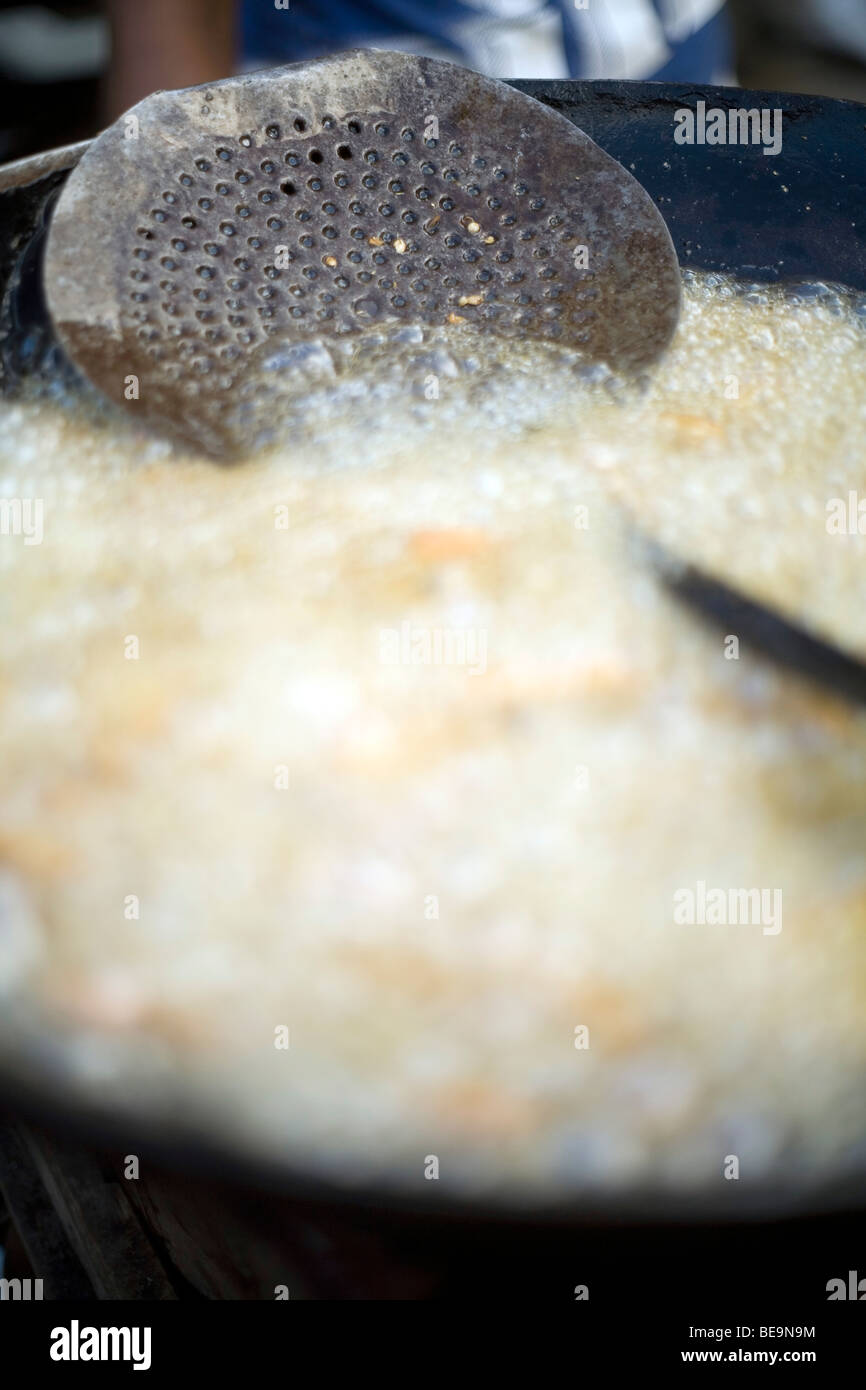 A vat of bubbling cooking oil and a ladle on a street food stall in Old