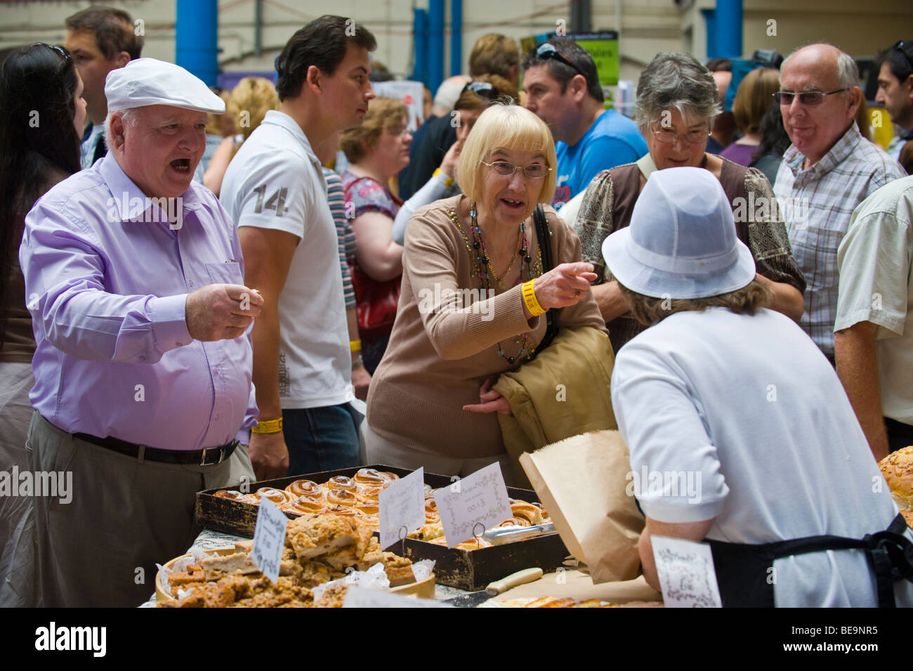 Customers queue to buy bread and cakes on bakers stall in Market Hall at Abergavenny Food Festival Monmouthshire South Wales UK Stock Photo