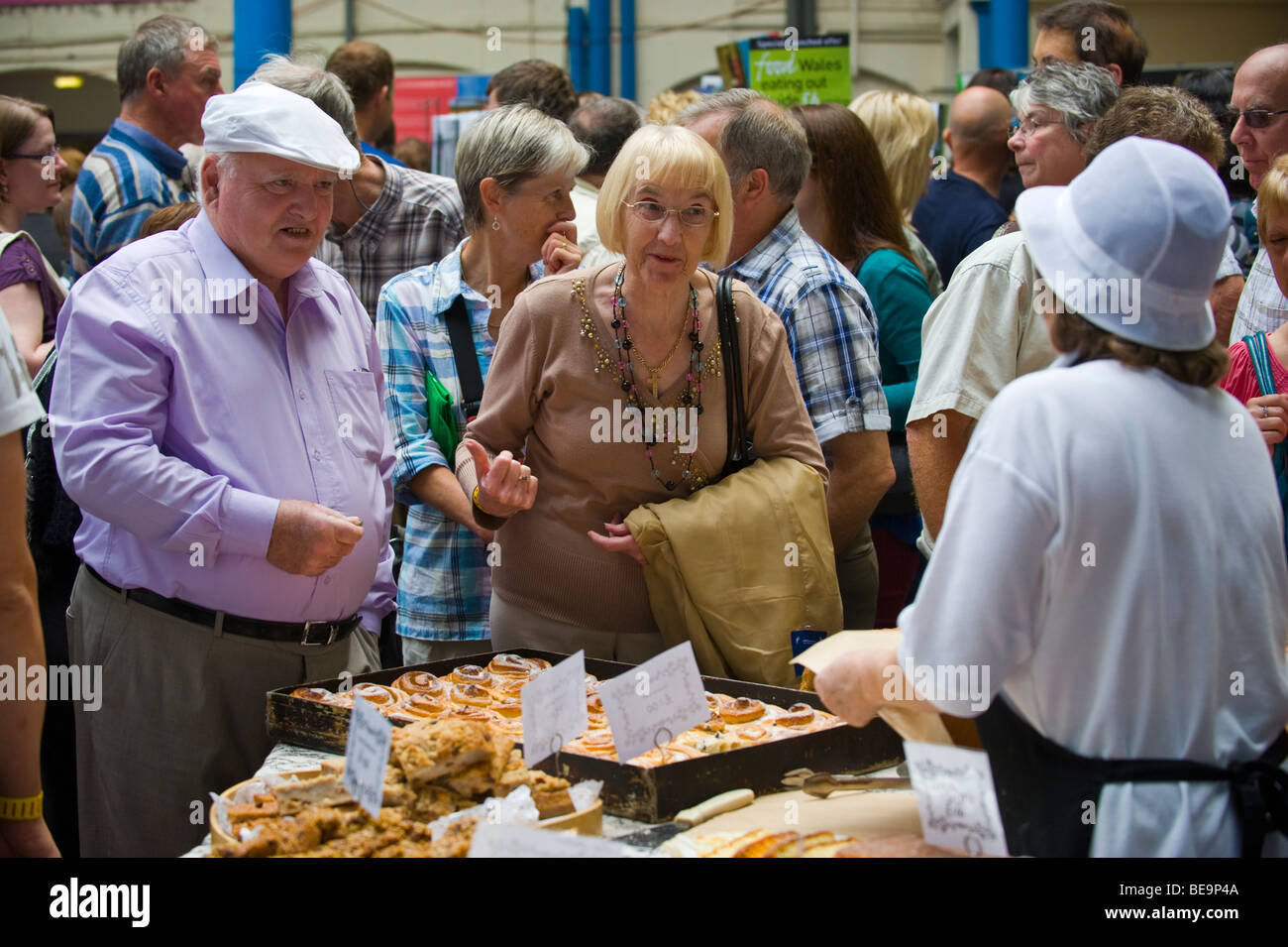 Customers queue to buy bread and cakes on bakers stall in Market Hall at Abergavenny Food Festival Monmouthshire South Wales UK Stock Photo