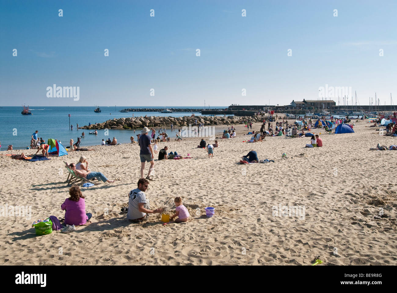 Holiday makers on the pebble beach at Lyme Regis, Dorset Stock Photo