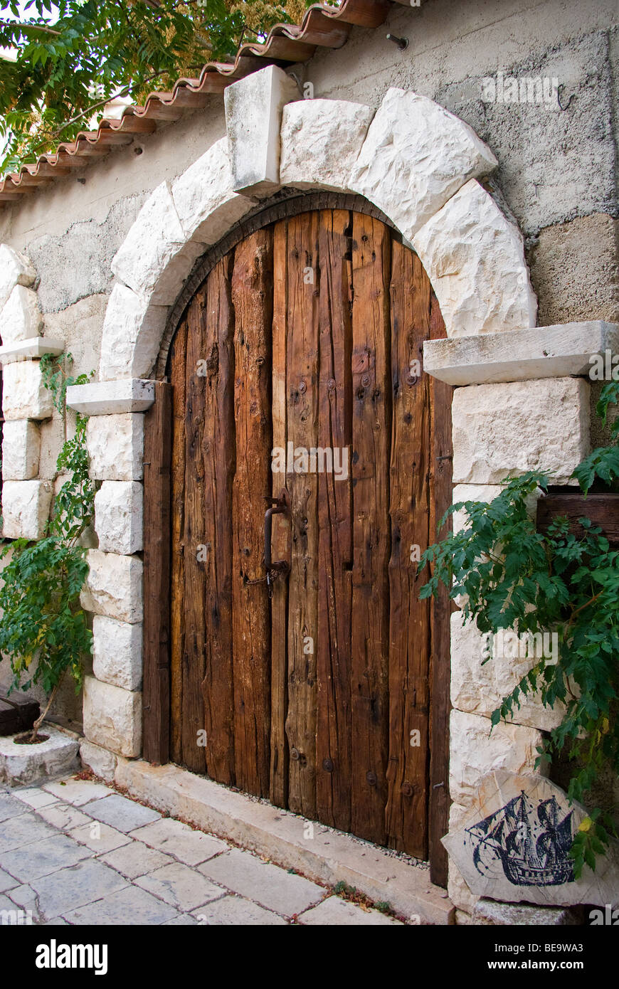 Croatia; Hrvartska; Kroatien, Hvar Island; Strai Grad, aged wooden door, with rounded top, in stone wall Stock Photo