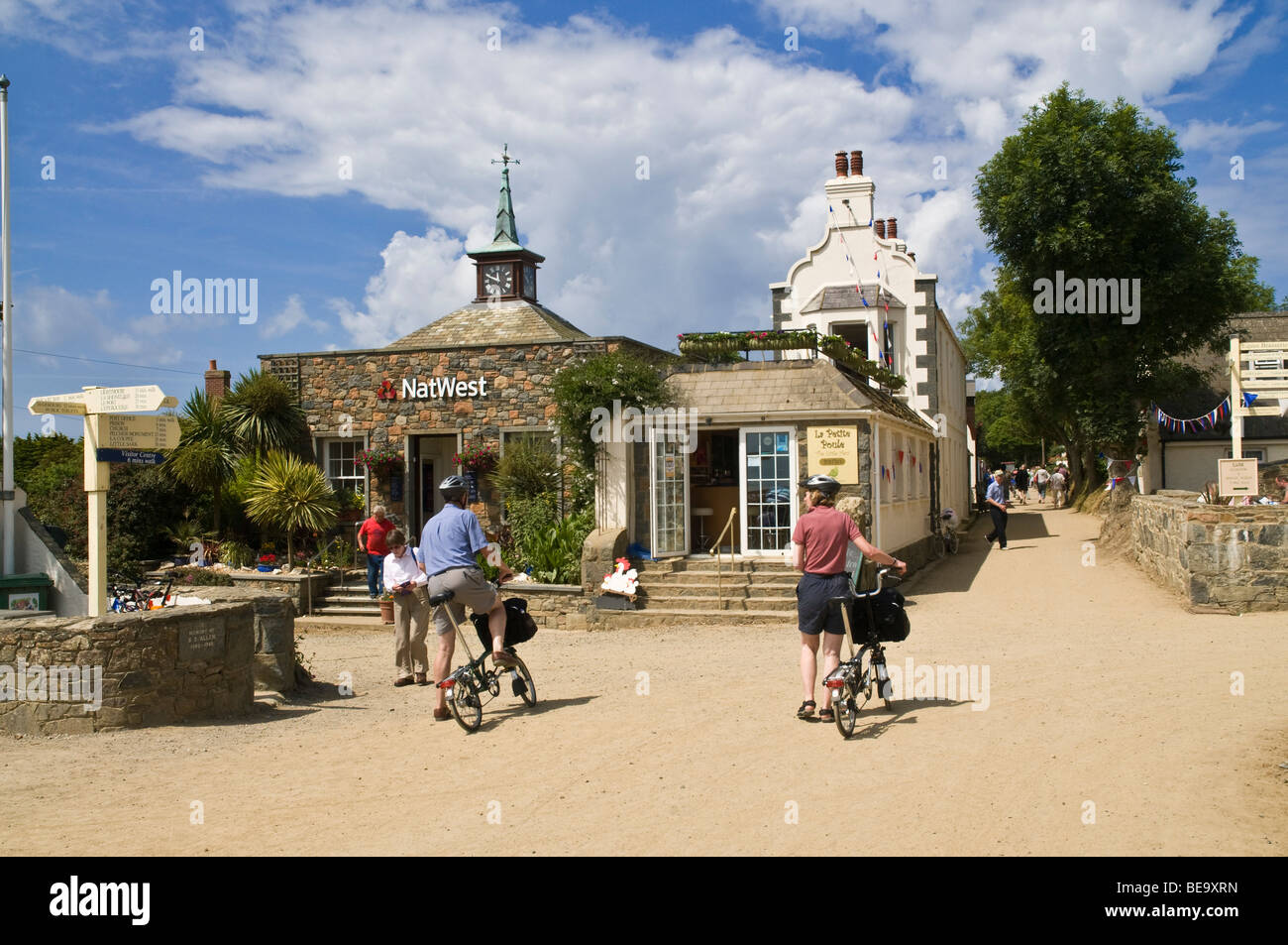 dh  SARK VILLAGE SARK ISLAND Cycling tourists village main street tourist bicycles couple capital town channel islands Stock Photo