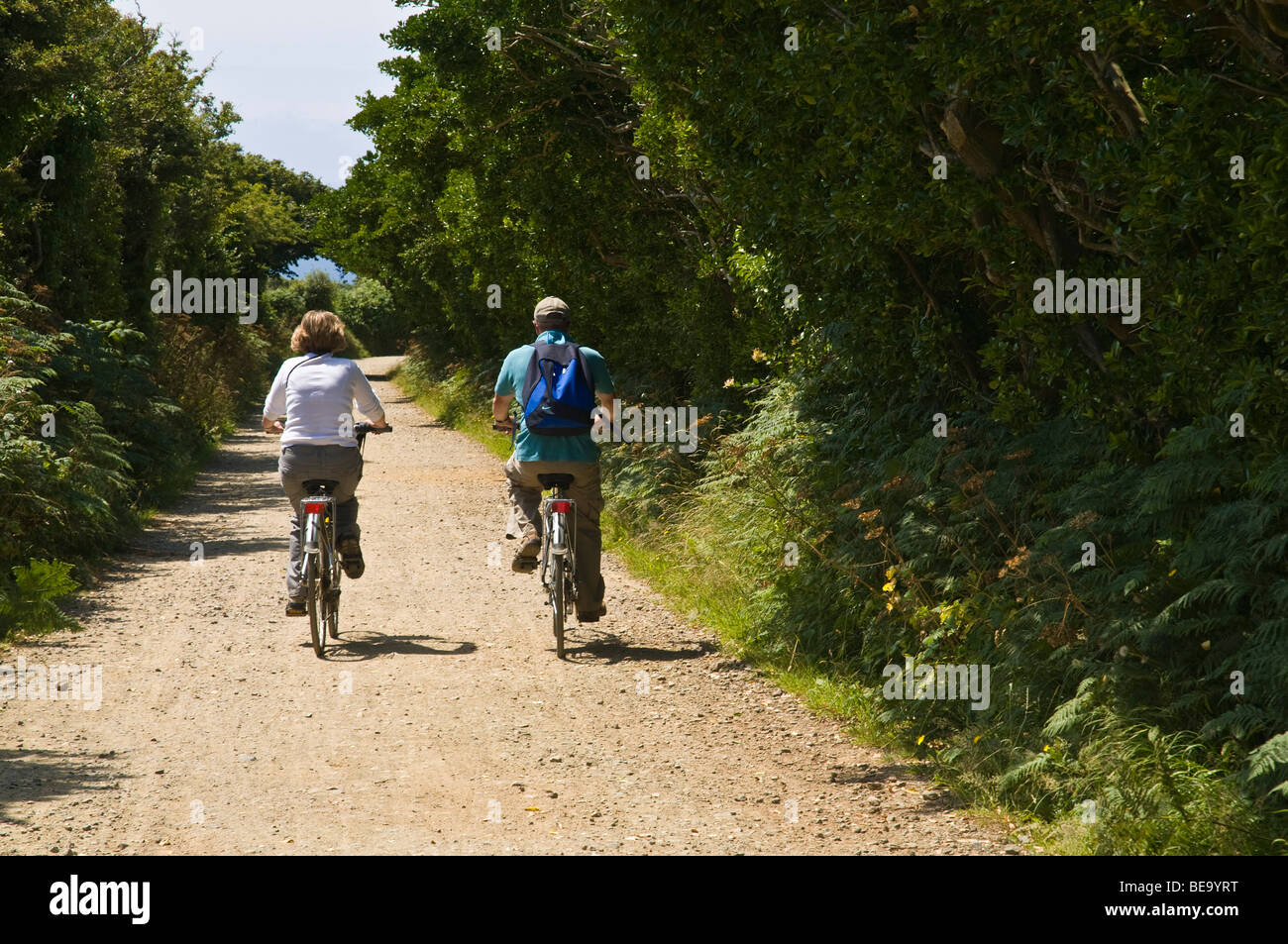 dh  SARK SARK ISLAND Two Tourist couple riding bicycles in country lanes cycling road channel islands 2 cyclists cyclist holiday cycles Stock Photo