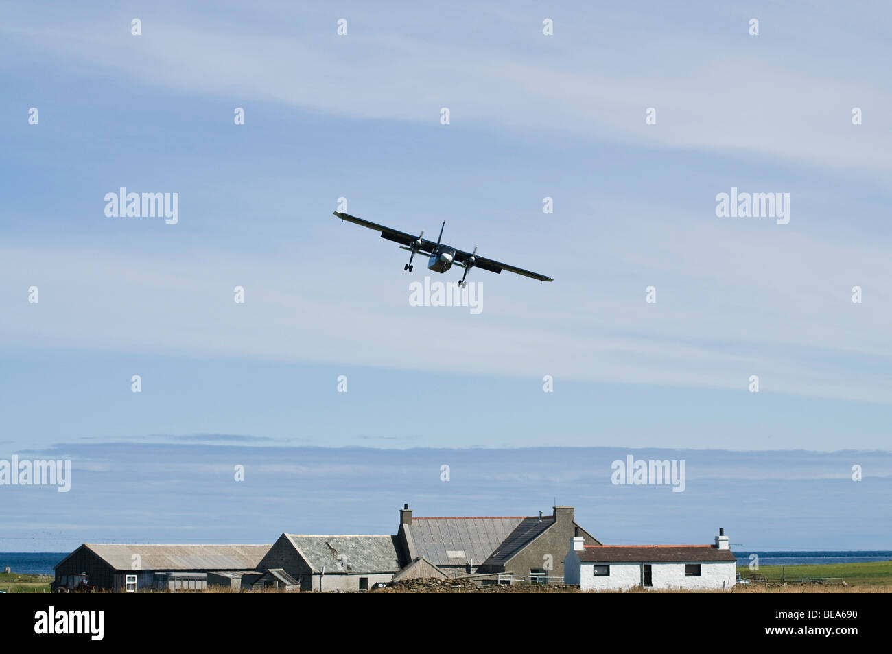 dh Britten Norman Islander NORTH RONALDSAY ORKNEY ISLES Loganair airplane above cottage small plane landing island house remote Stock Photo