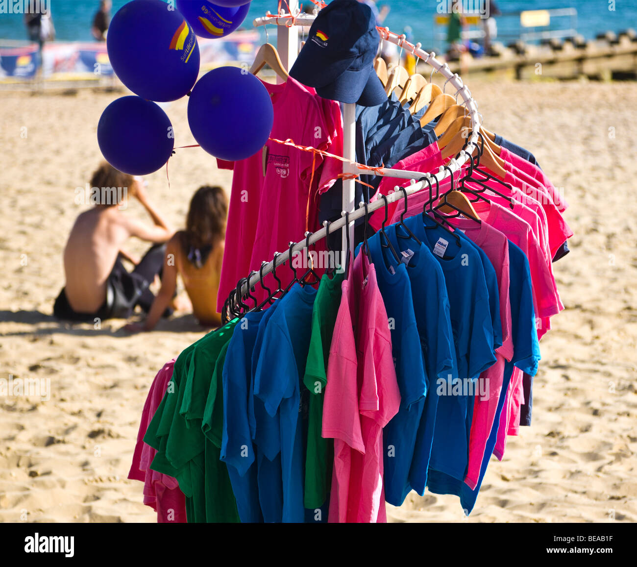 Colourful t-shirts on hangers, for sale on Bournemouth beach. Dorset. UK. Stock Photo