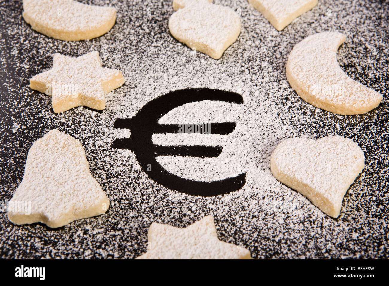 The Euro symbol in powdered sugar surrounded by various shaped cookies Stock Photo