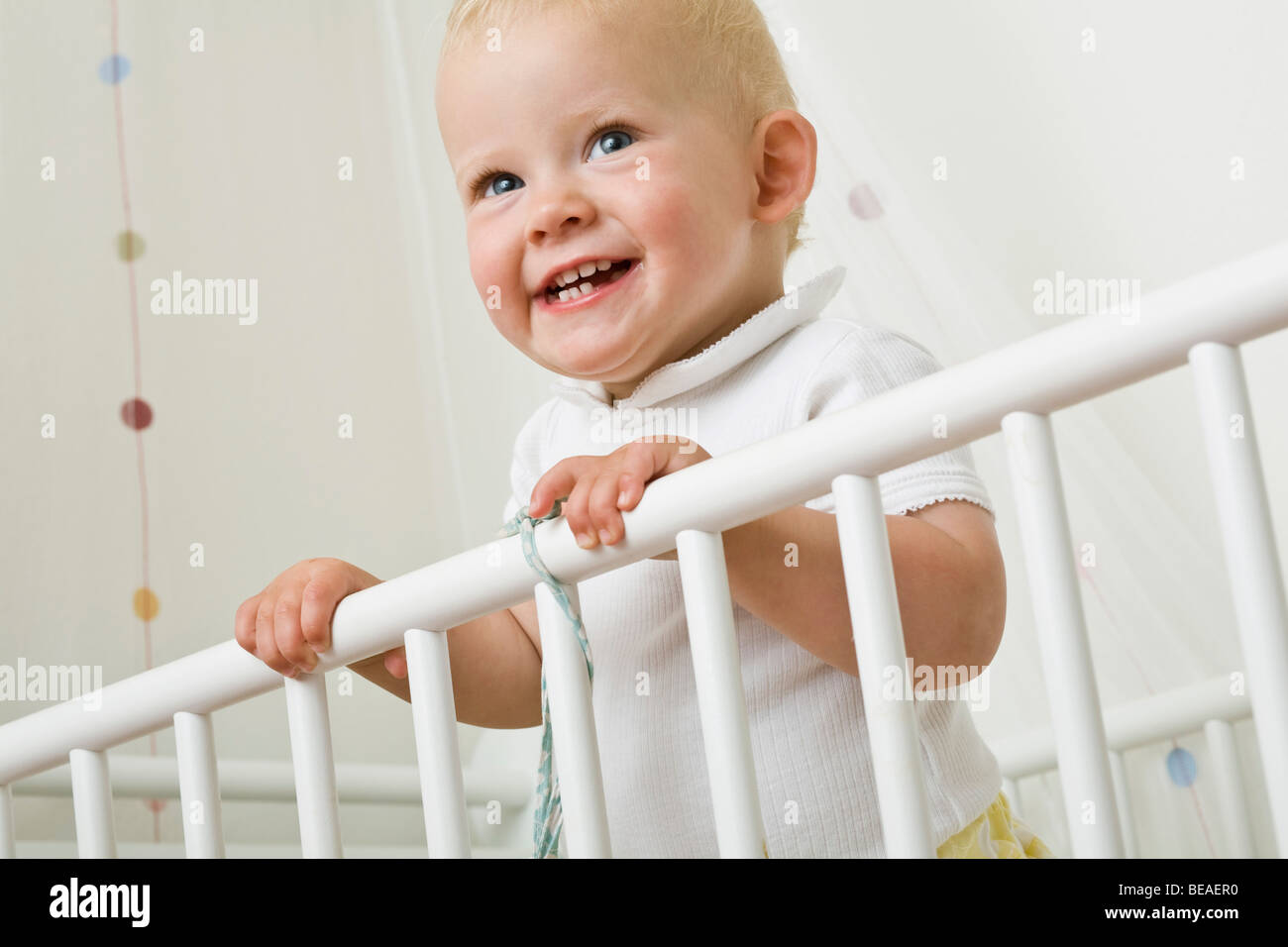 A toddler standing in a baby crib Stock Photo