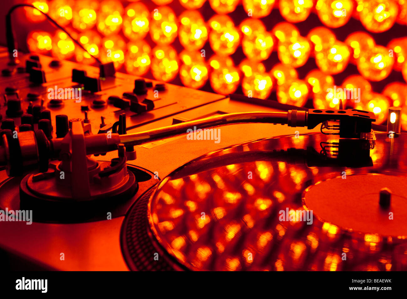 A turntable and sound mixer illuminated by lighting equipment Stock