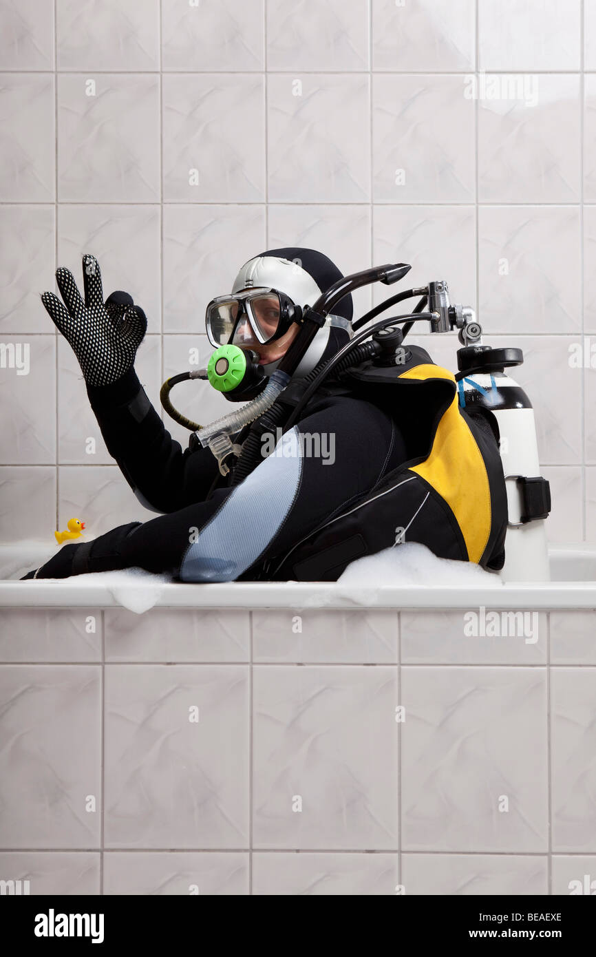 A scuba diver sitting in a bubble bath giving the OK sign Stock Photo