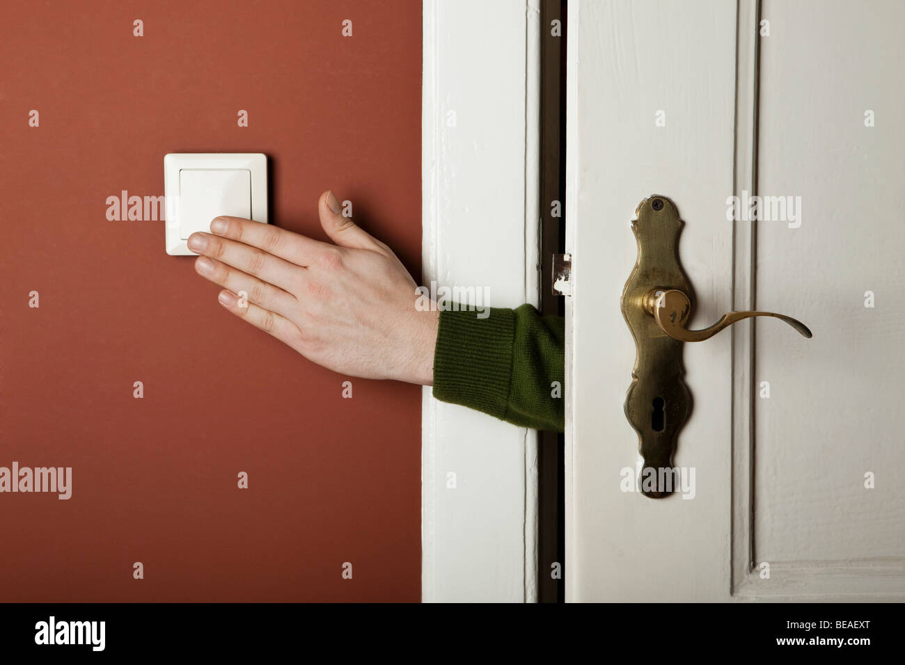 A hand turning off a light switch Stock Photo