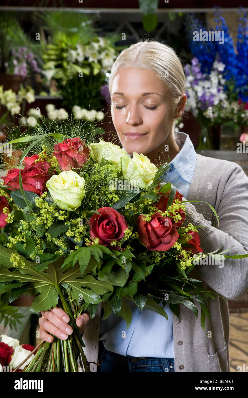 A woman smelling a bouquet of flowers in a florists Stock Photo Alamy