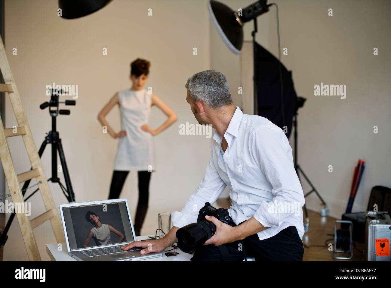 A photographer using a laptop on set of a fashion shoot Stock Photo Alamy