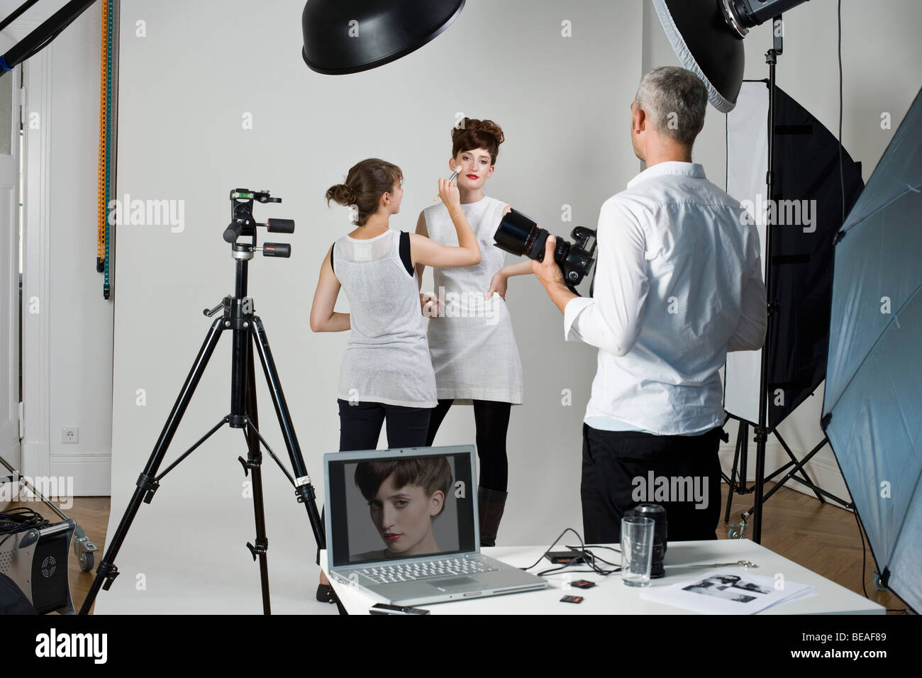 A photographer, model and make-up artist on set of a fashion shoot Stock Photo