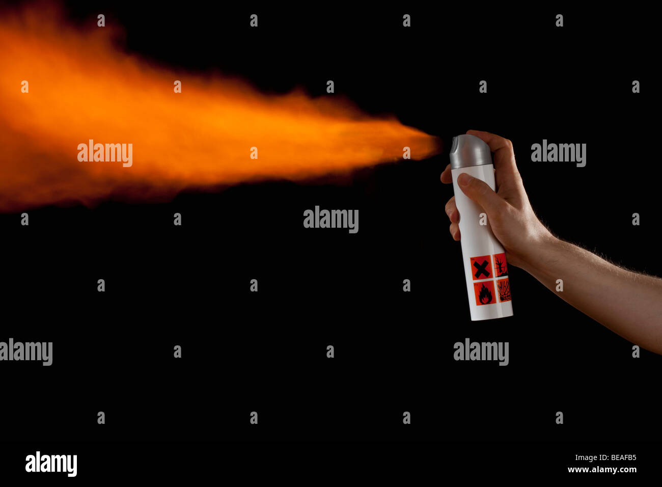 A hand spraying flames from an aerosol can, studio shot Stock Photo
