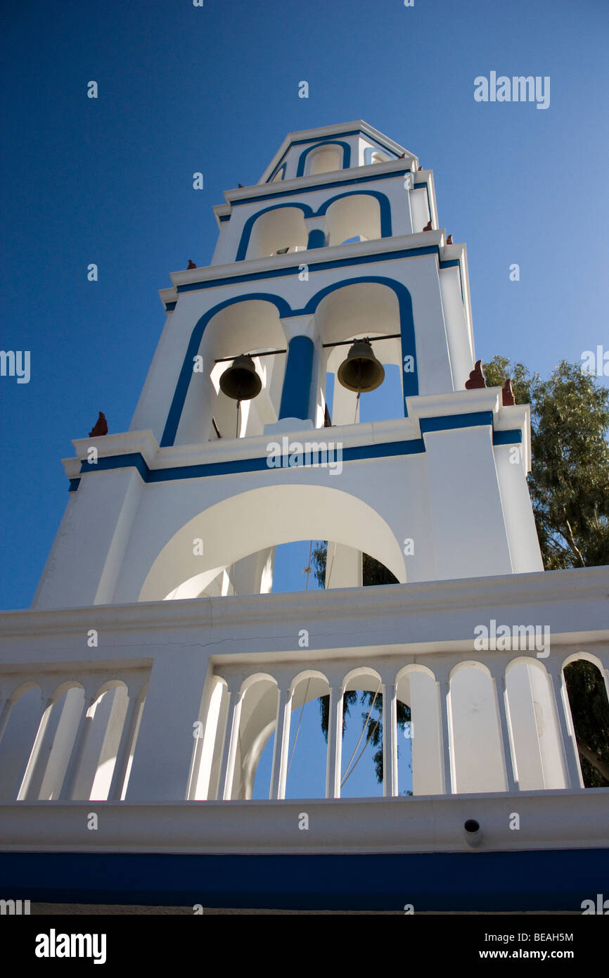 Beautiful characteristic white church bell tower against blue sky, in the town of Kamari, Santorini, Greece. Stock Photo