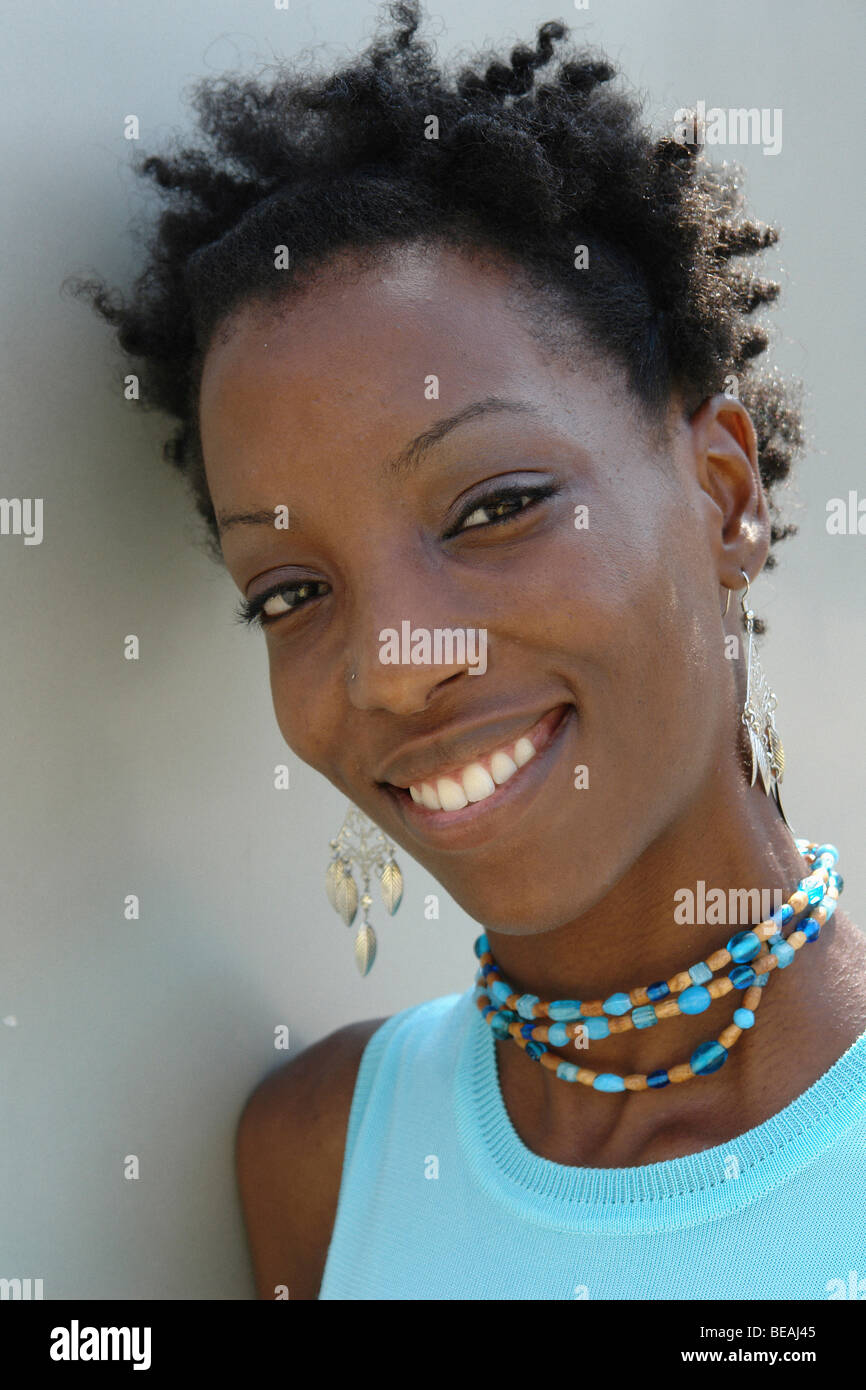 Softly Lit Fashion Portrait of an African American Woman Wearing an Pastel Aqua Sleeveless Top and Jewelry She is Smiling Stock Photo