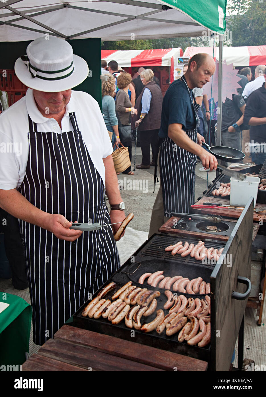 Butcher cooking sausages using temperature probe at open air food festival Abergavenny Wales UK Stock Photo