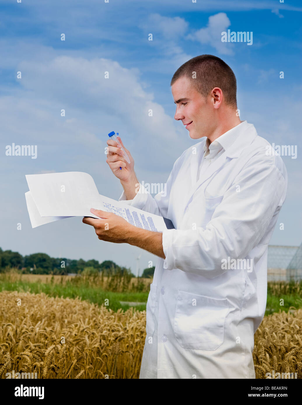 Agriculture scientist making notes in the field with greenhouses in background Stock Photo