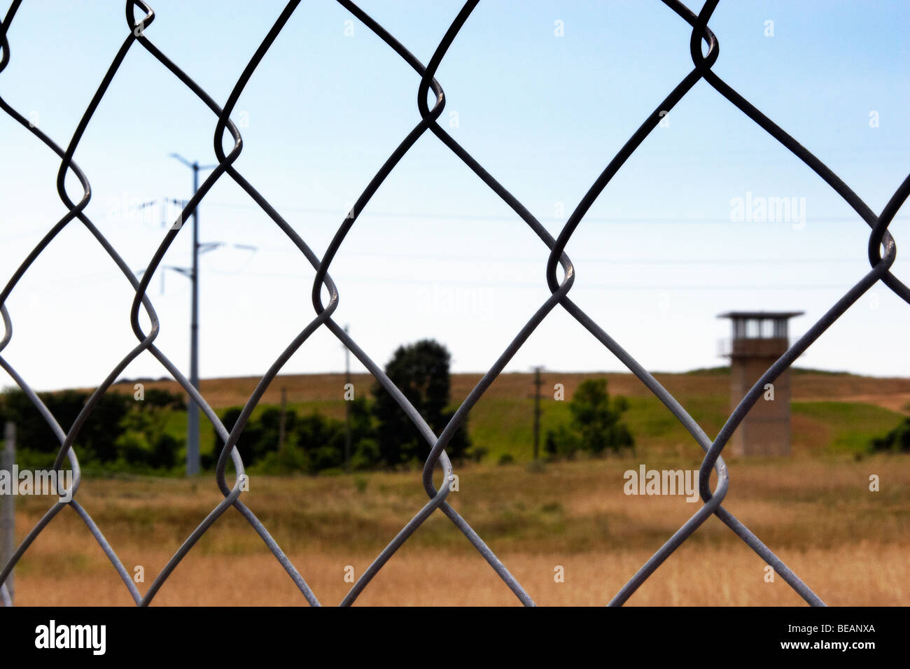 A chain-link fence with guard tower in the distance surrounding the former Lorton Correctional Complex, Lorton, Virginia. Stock Photo