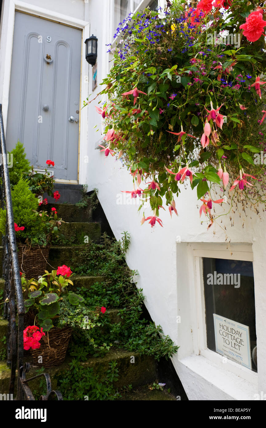 Floral Hanging Baskets Of Flowers Over Steps To A Grey Door At A