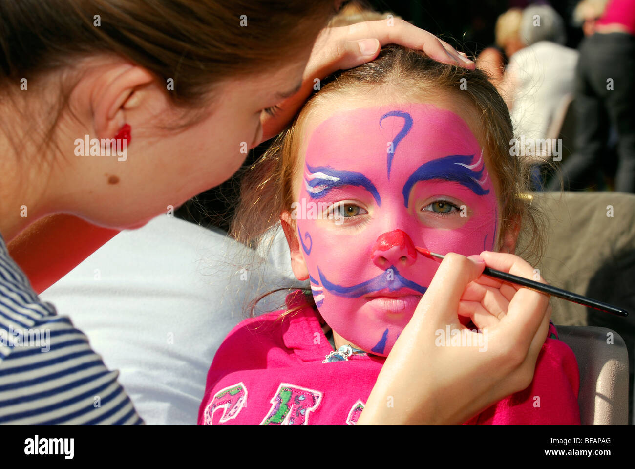 4 year old girl having her face painted at Trotton village fete, Hampshire, UK. Stock Photo