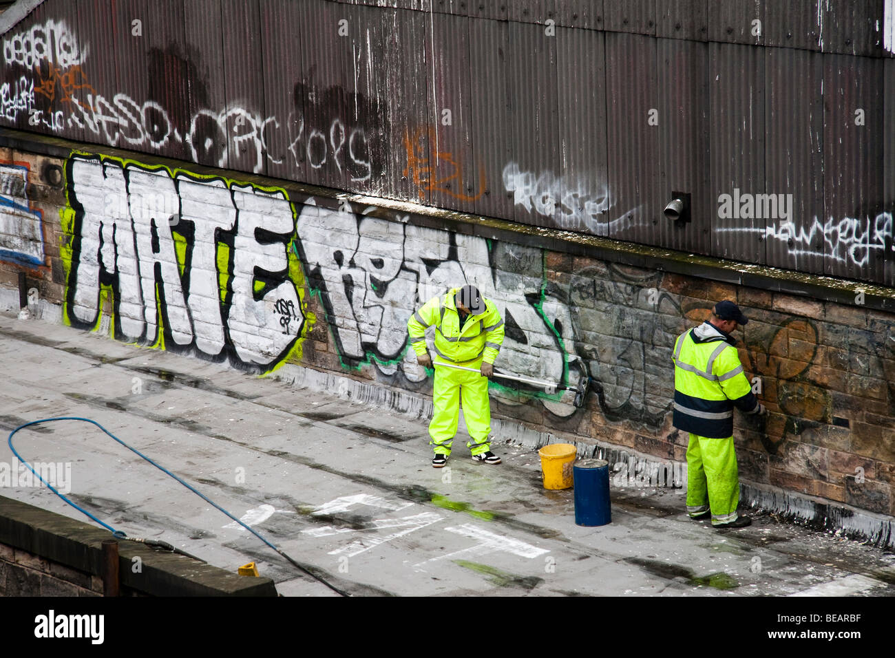 Two men removing graffiti paint from a wall Stock Photo Alamy