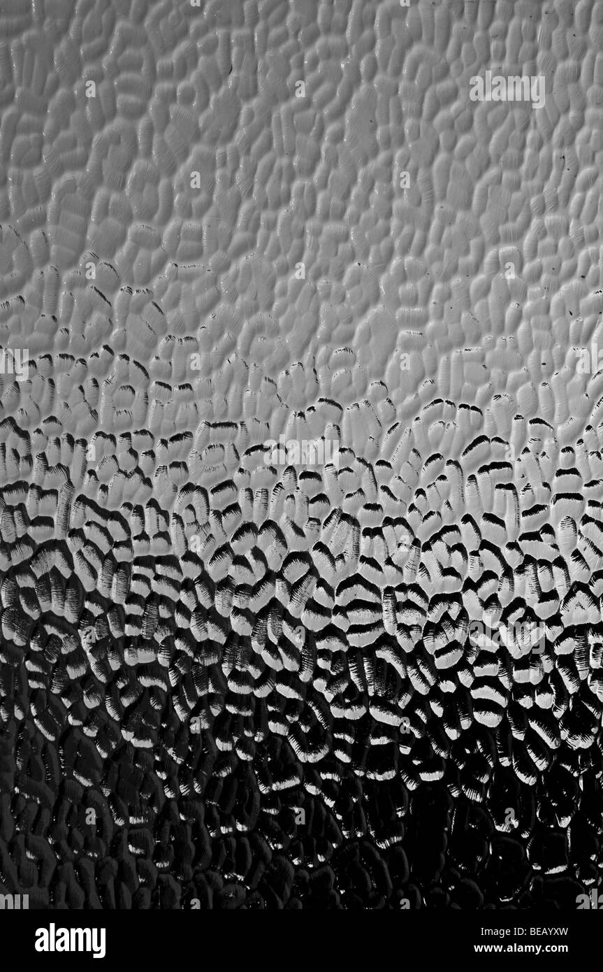 A textured glass window, neutral shades of greys through to black.  Abstract background. Stock Photo