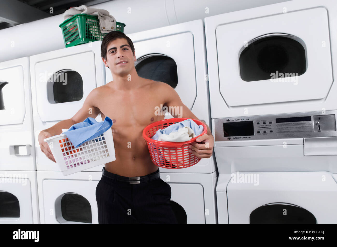 Man carrying laundry baskets in a laundromat Stock Photo Alamy