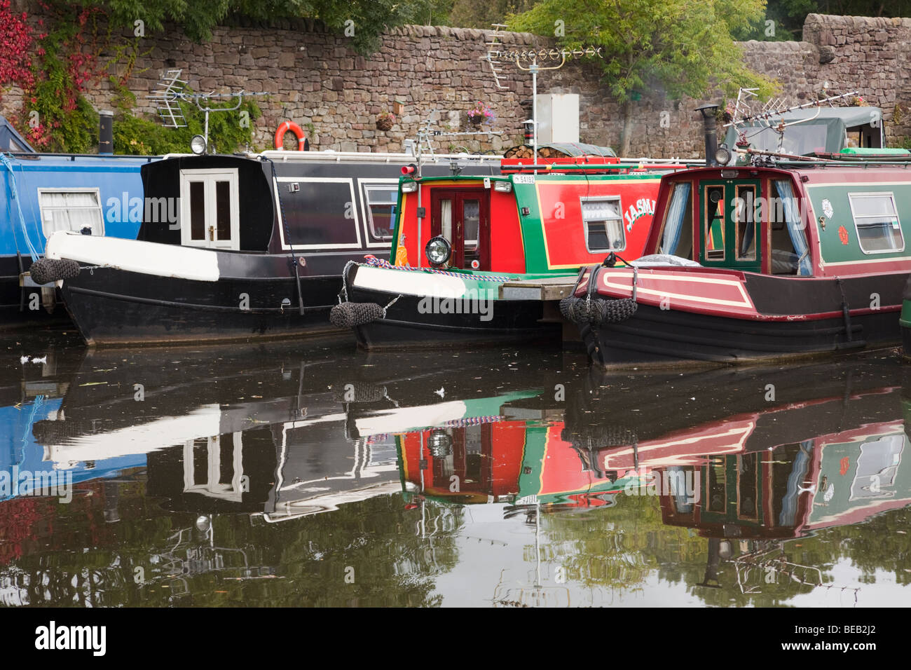 Galgate, Lancashire, England, UK, Europe. Moored narrowboats reflected in the water of the Lancaster canal basin. Stock Photo