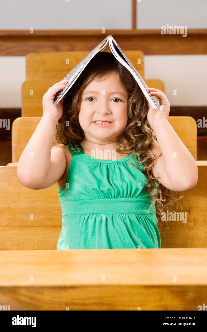 Schoolgirl holding a book on her head in a classroom Stock Photo - Alamy