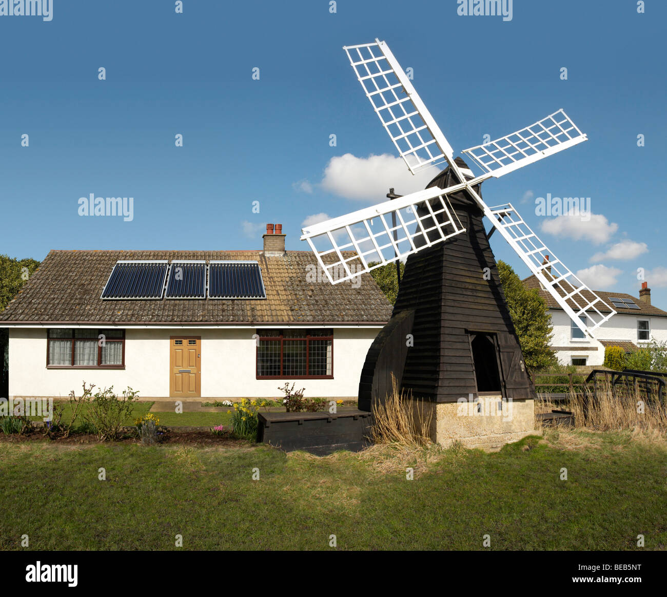 English cottage fitted with solar panels and old windmill England UK Stock Photo