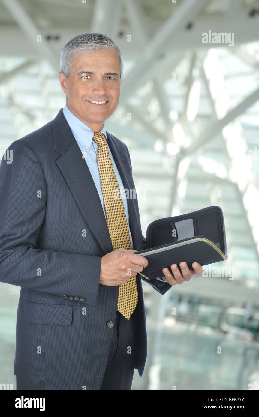 Standing Businessman with Planner Notebook in Office Setting Stock Photo