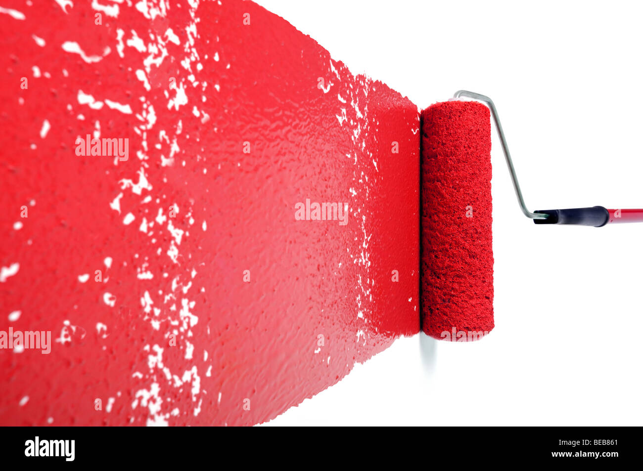 Pain roller with red paint on white wall Stock Photo
