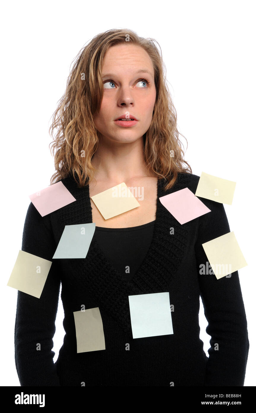 Young businesswoman overwhelmed with adhesive notes Stock Photo