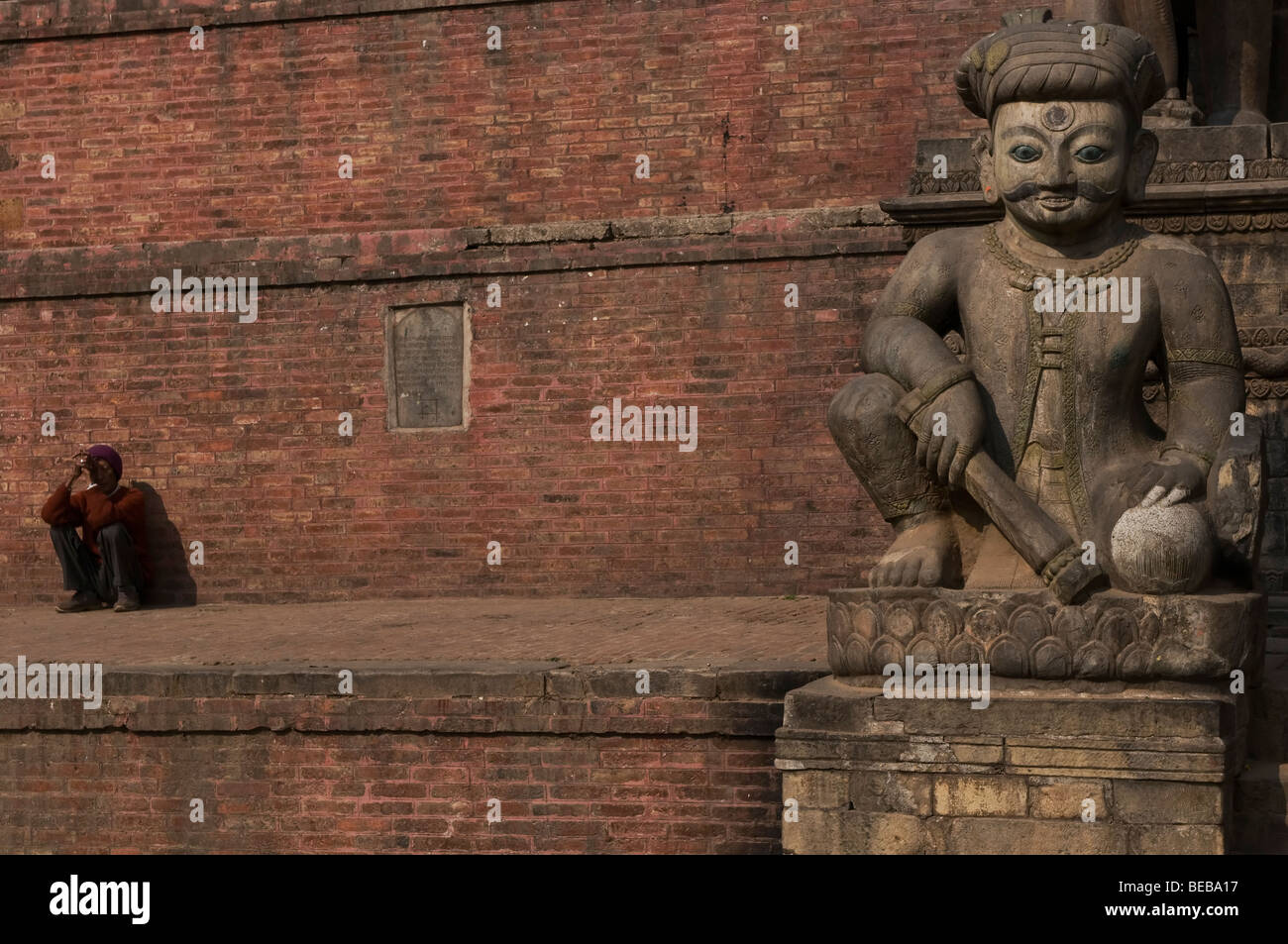 Local man, and a Stone carved statue, Bhaktapur, Nepal Stock Photo