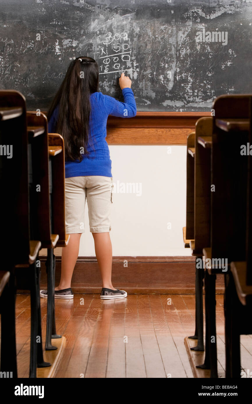 Schoolgirl writing on a blackboard in a classroom Stock Photo
