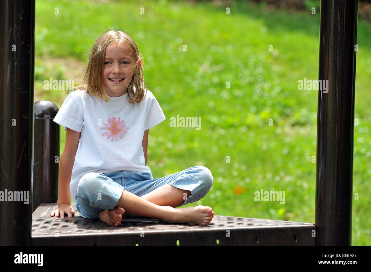 Young girl smiling sitting on a playground Stock Photo - Alamy