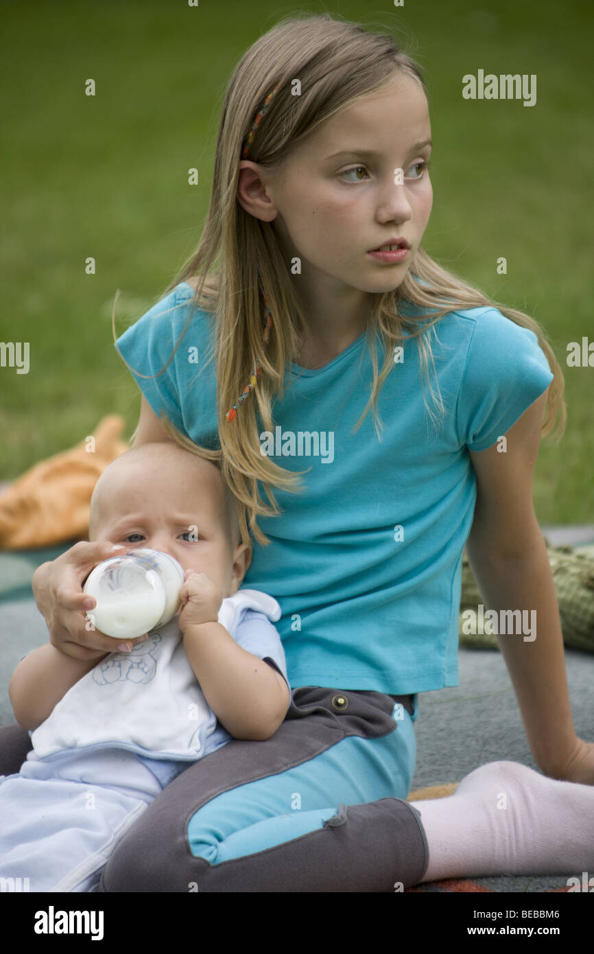 Unhappy PRETEEN GIRL nursing her brother with bottle Stock Photo - Alamy