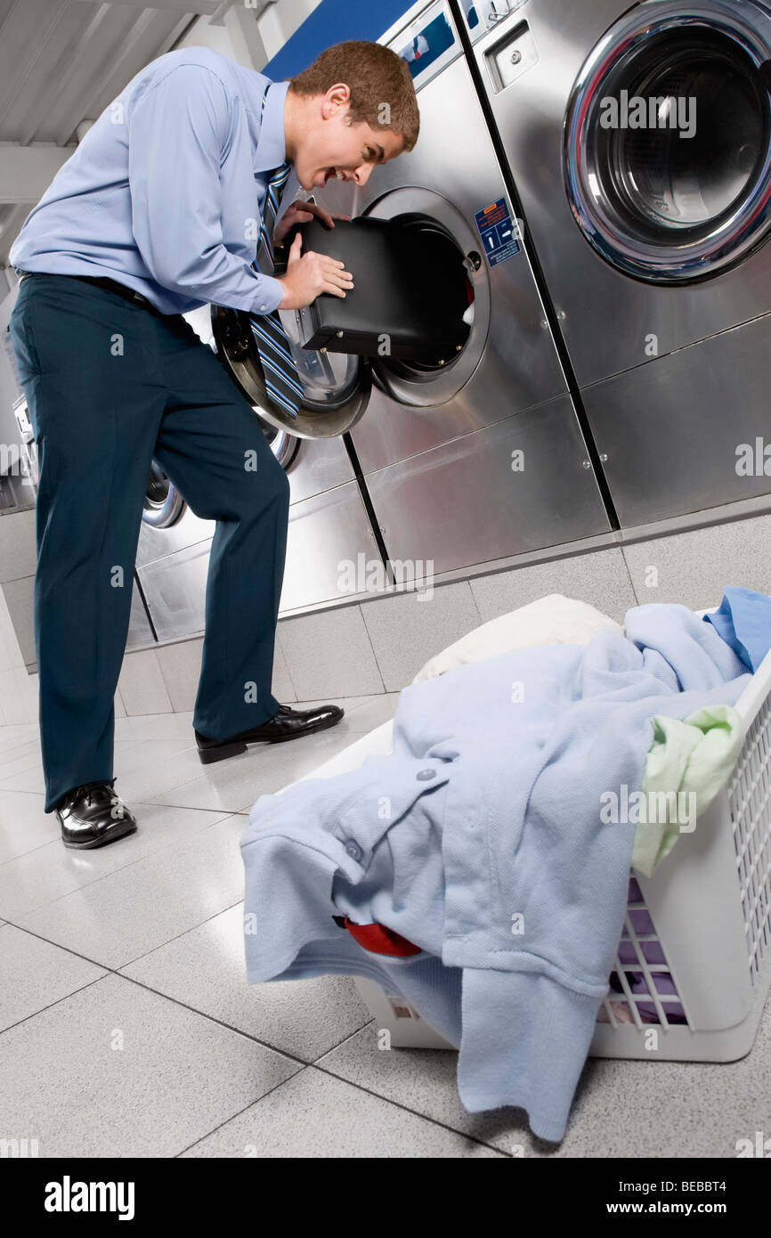 Businessman putting a briefcase into a washing machine Stock Photo