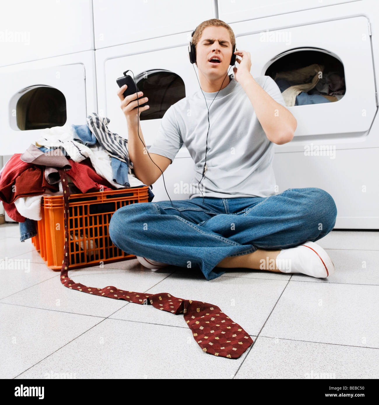 Man listening to an MP3 player in a laundromat Stock Photo